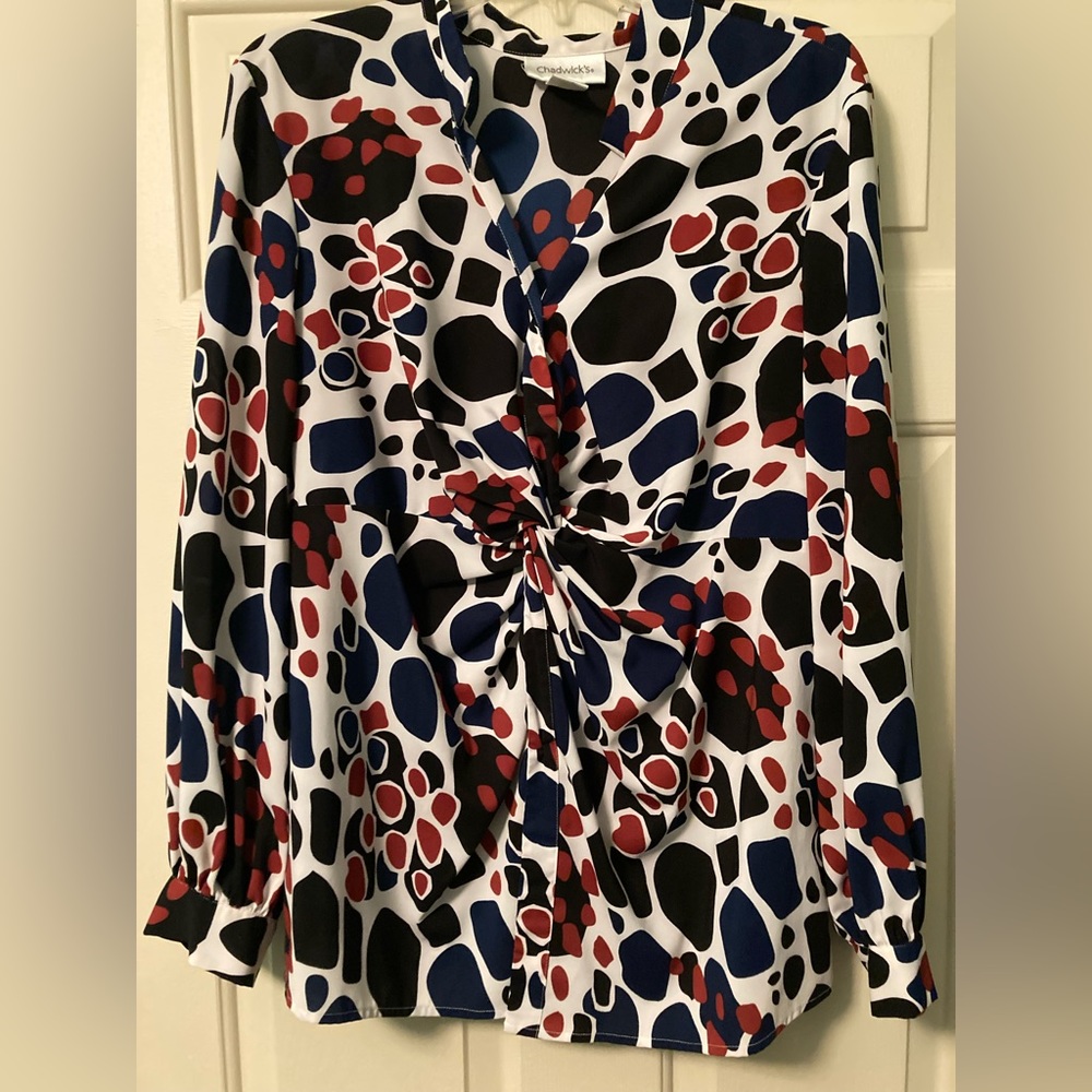 Blouse with a twist front style, has a button front. Navy,Red and black print.